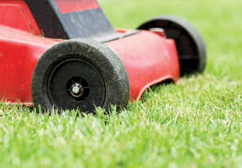 Close up of a red lawnmower's front wheels on a finely manicured lawn