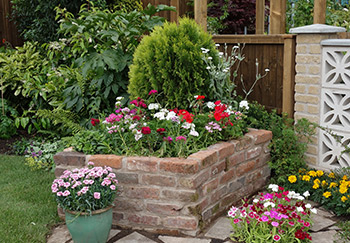 A raised bed constructed from bricks and filled with colourful flowers