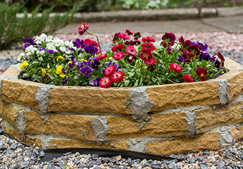A brick raised bed in the shape of a decagon filled with lovely colourful flowers